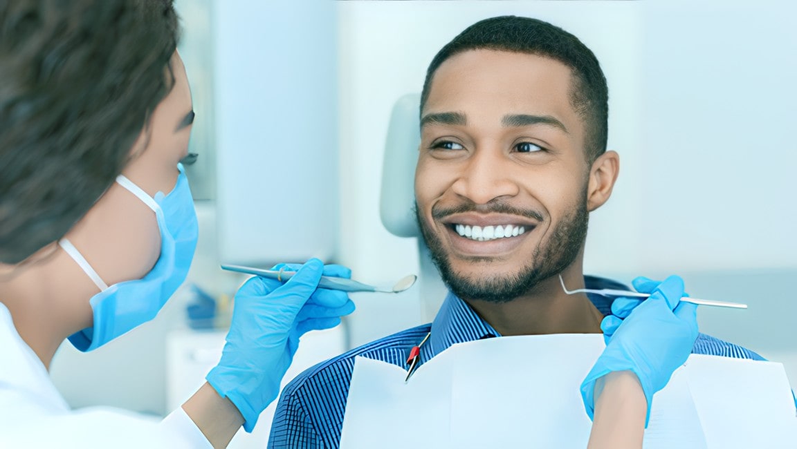 Smiling black male in a dentist chair, smiling with trust at his doctor.